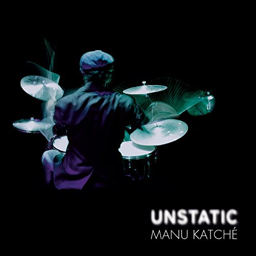 Drummer Manu Katché playing a kit with glowing cymbals, dark background.
