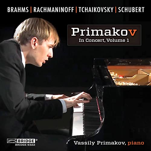 Pianist Vassily Primakov in concert, playing a black grand piano.
