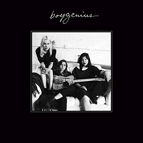 Black and white photo of three women with guitars on a couch.