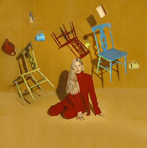 Woman in red kneels amidst floating, colorful chairs and objects.