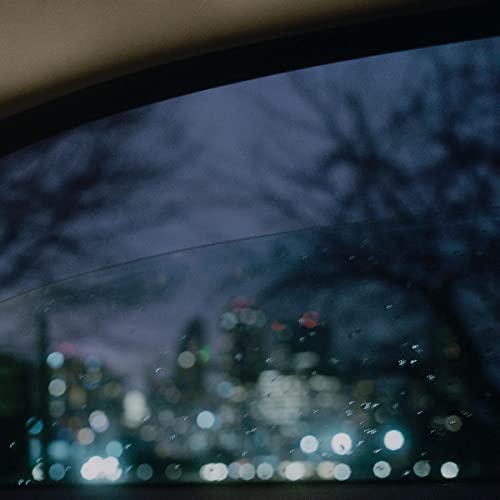 Raindrops on glass with blurred city lights in the background.