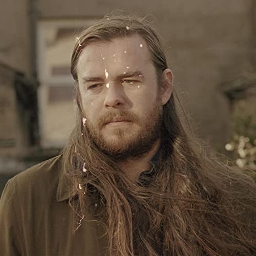 Close-up of John Francis Flynn with long hair and beard, looking forward.