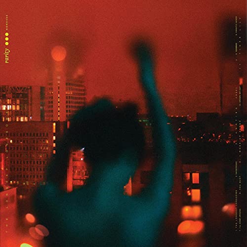 Blurred figure with raised arm overlooks a city at night.