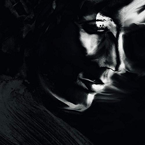 Black and white close-up of a face, partially obscured in shadow.