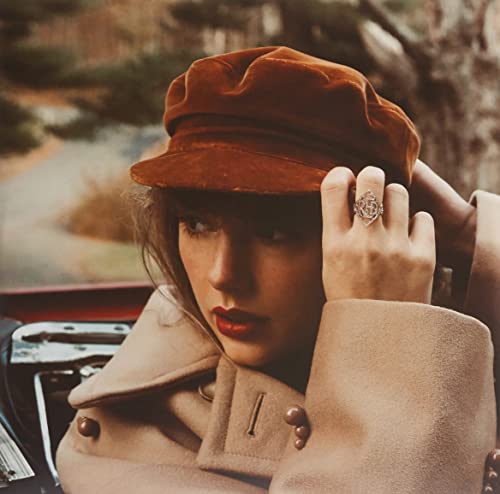 Taylor Swift wearing a red hat and ornate ring, close-up portrait.