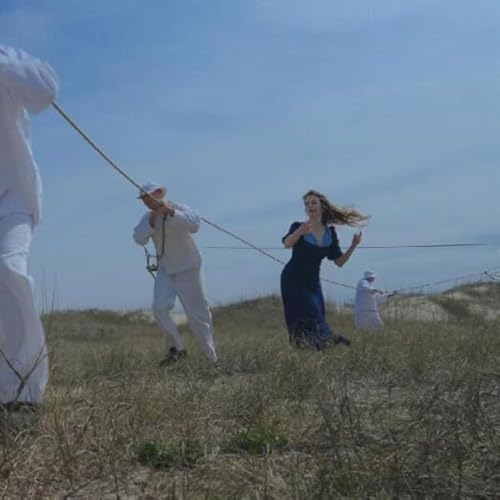 People in light and dark clothing pulled by ropes in a field.