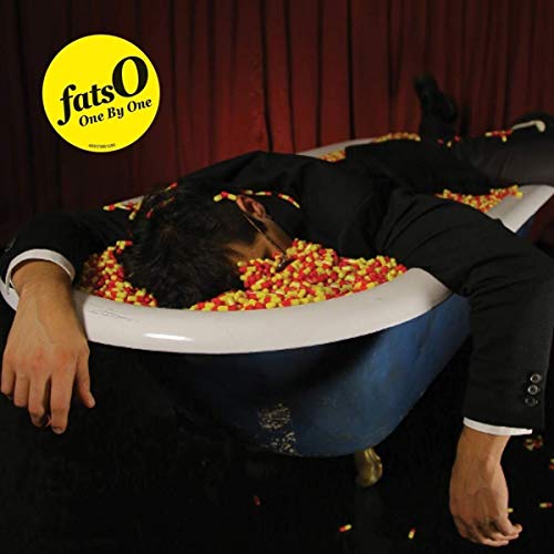 Person in a suit submerged in colorful sprinkles within a bathtub.