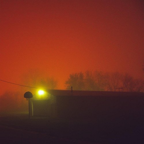 Red sky over a dark building with a basketball hoop in foreground.