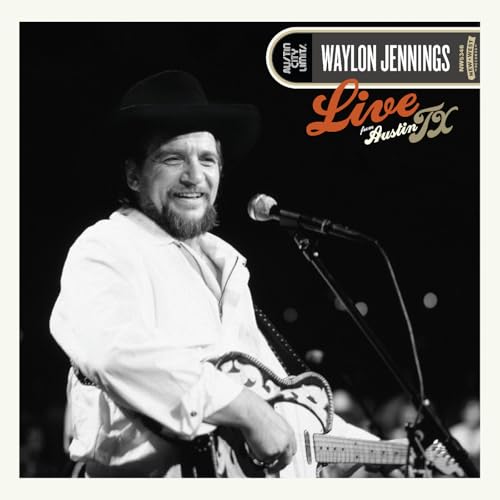 Black and white photo of Waylon Jennings playing guitar and singing into a microphone.