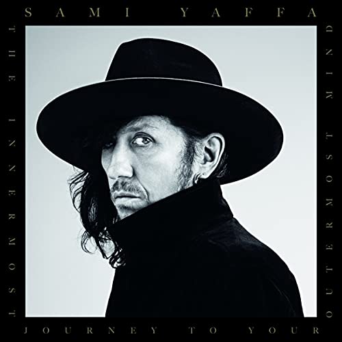 Black and white portrait of Sami Yaffa wearing a black hat.