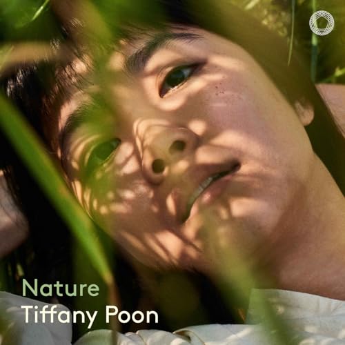 Close-up of Tiffany Poon smiling, partially obscured by green foliage.