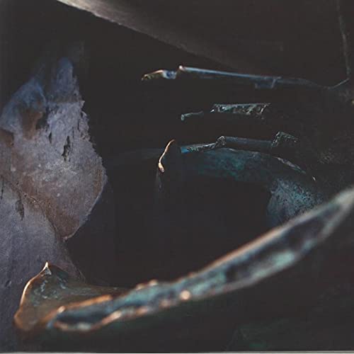 Dark, textured image of rock formations with a hint of blue light.