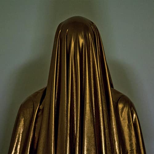 Figure draped in shiny, dark gold fabric with obscured face.