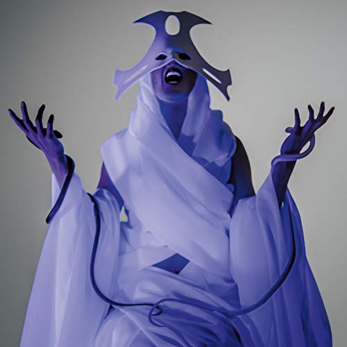 Person in white robes and a geometric headpiece, arms raised.