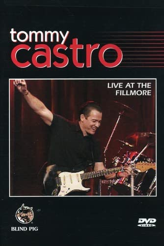 Tommy Castro playing guitar on stage during a live concert performance.