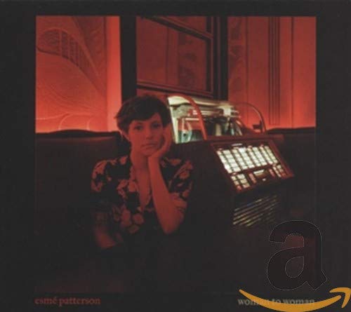 Woman with hand on cheek sits before a vintage jukebox, red tones.