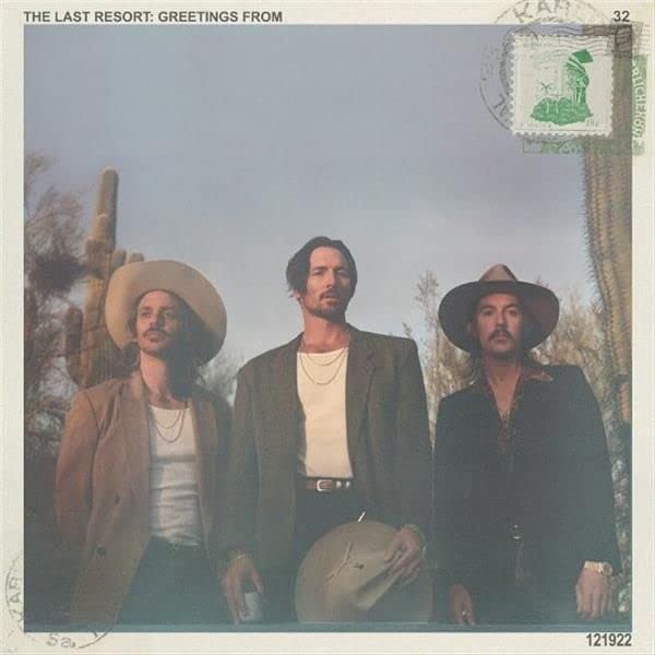Three men in western wear stand together outdoors with cacti behind them.