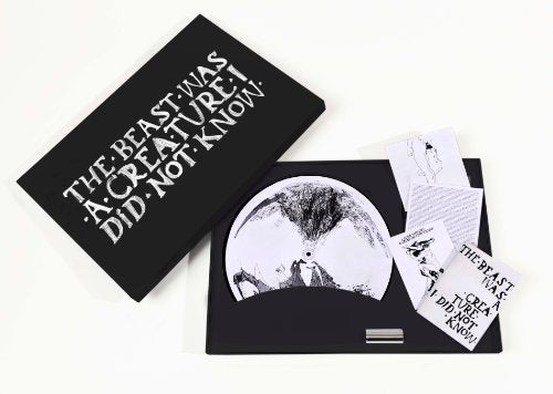 Open box set containing a vinyl record and printed inserts on a white background.