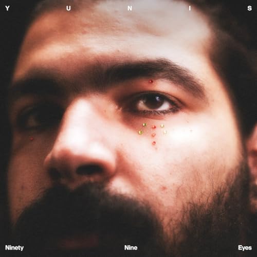 Close-up of a man’s face with colorful dots around one eye.