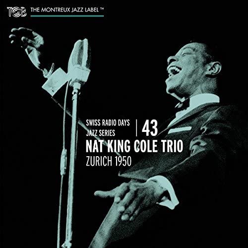 Nat King Cole singing into vintage microphones, black and white photo.