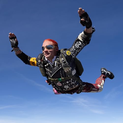 Skydiving with red hair, black and red jumpsuit, and sunglasses.