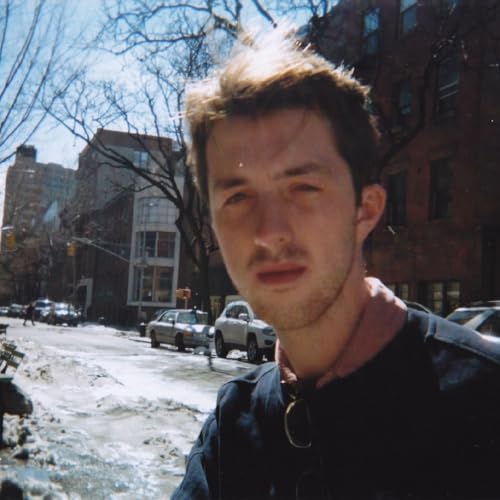 Close-up portrait of a young man with a city street background.