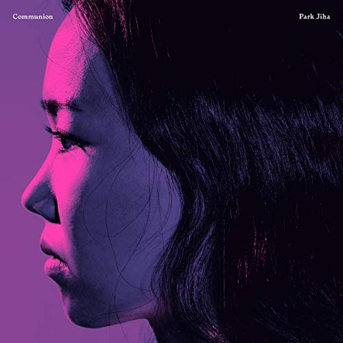 Close-up of a woman’s face in pink and purple tones, album cover.