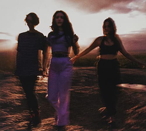 Three women walking towards the sunset in a blurry landscape.