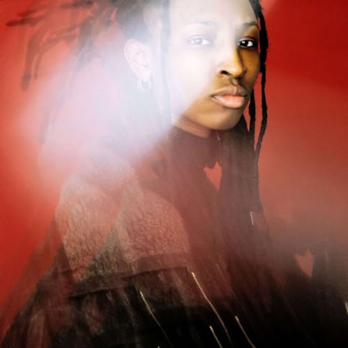 Close-up portrait of Luci with dreadlocks, against a red, smoky background.
