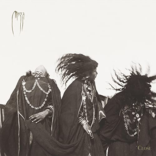 Black and white photo of three people with long hair and necklaces.