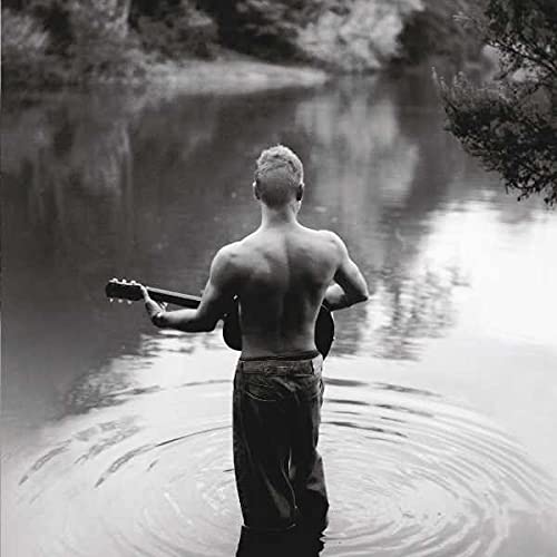Back view of Sting with a guitar, standing in water.