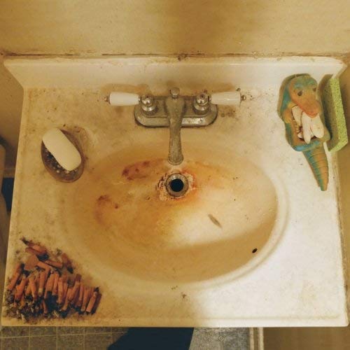 Vintage vinyl record resting on a stained, old bathroom sink.