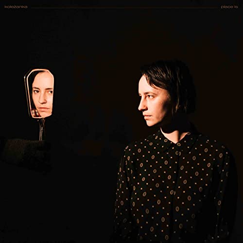 Dark album cover featuring a woman and her reflection in a mirror.