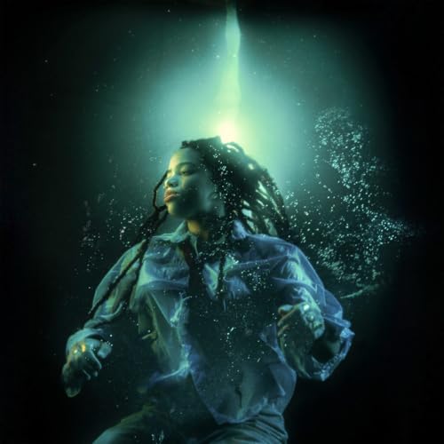 Woman with dreadlocks submerged in water, illuminated by bright light.