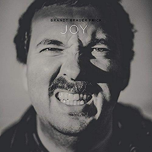 Black and white portrait of a smiling man, album cover for Brandt Brauer Frick.