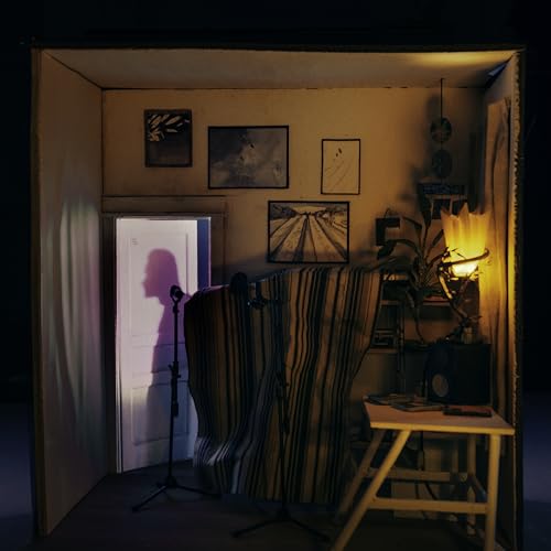 Small room with striped armchair, artwork, and a bright doorway.