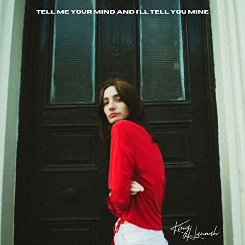 Woman in red stands before a dark doorway, album cover.