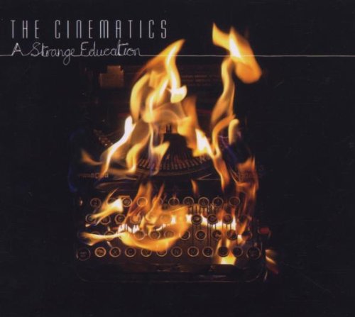 CD cover: burning typewriter with flames, text “The Cinematics – A Strange Education”.