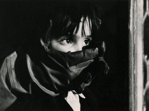 Black and white film still of a young child holding a toy gun.