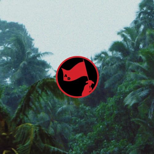 Red circle with black and white flag design over blurred greenery.