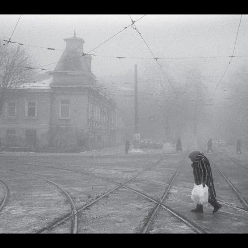 Black and white image of a person walking down a foggy street.