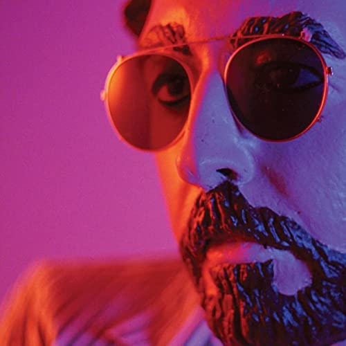 Close-up of a man with sunglasses and dark, textured facial hair.