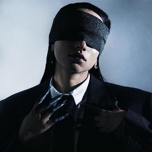 Person with a blindfold and suit, against a light blue background.