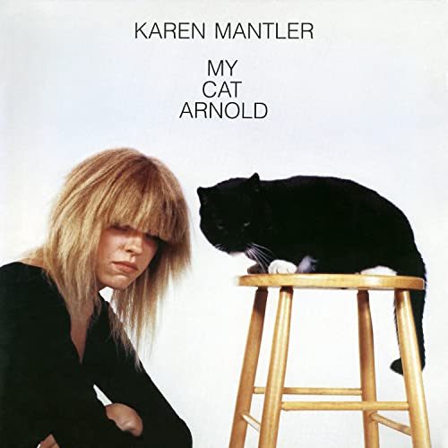 Woman with blonde hair and a black cat on a stool.