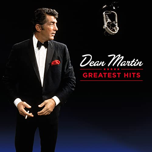 Dean Martin in a tuxedo standing near a microphone on a black background.