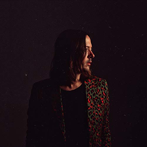 Portrait of a man with long hair wearing a leopard print jacket.