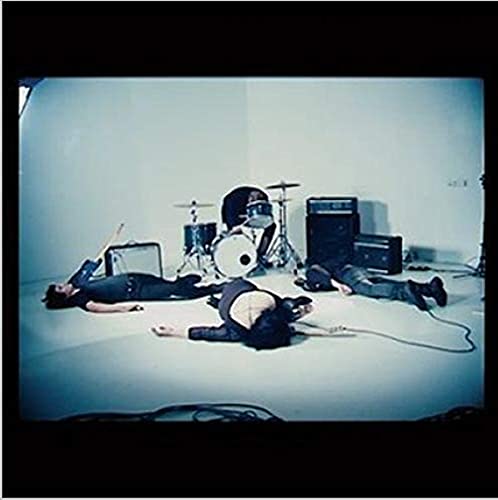 Three people lie motionless around musical instruments in a studio.
