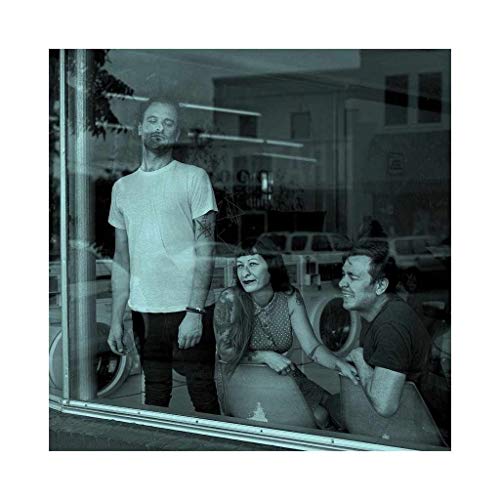 Three people seen through a window, teal-toned, looking towards the viewer.