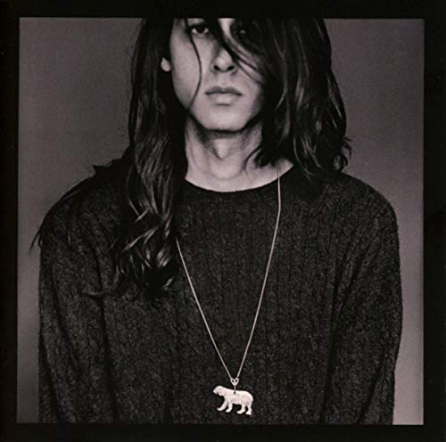 Black and white portrait of a person with long hair and a polar bear pendant.