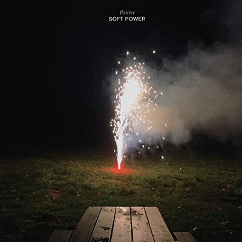 Fireworks exploding above a picnic table in a dark field.